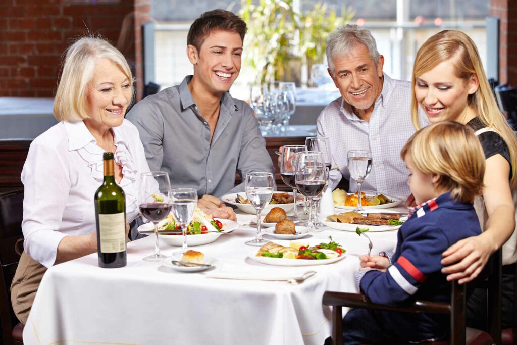 Glückliche Familie isst gemeinsam mit Kind und Großeltern im Restaurant